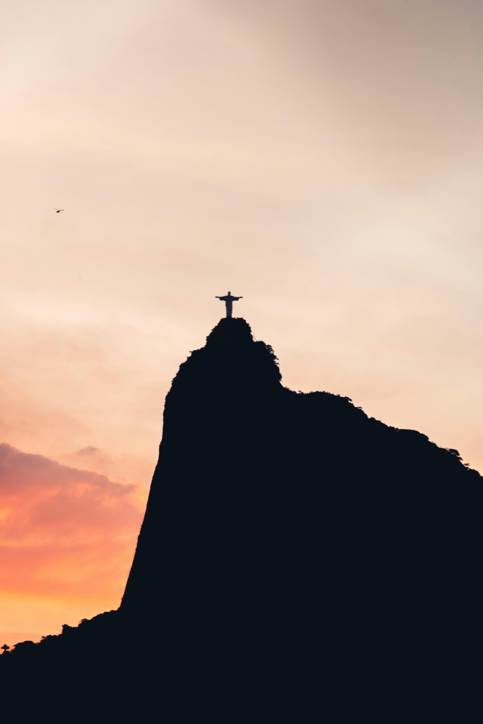 Silhouette of Christ the Redeemer against a vibrant sunset in Rio de Janeiro.